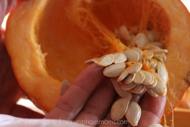 Close up of hand pulling seeds from pumpkin