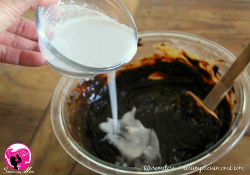 Close up pouring coconut milk in to melted chocolate